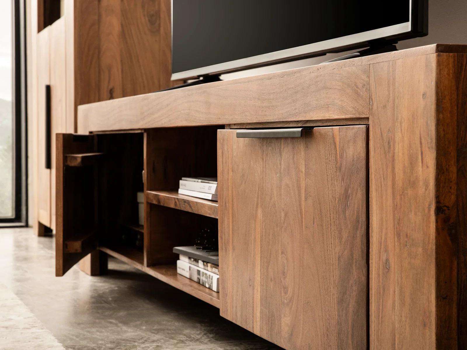 TV-Bank Osbon aus lackierter Akazie, 200×48×45 cm, 45°-Freisteller mit 2 Türen (geöffnet), 2 Fächern und dezenten Griffen.