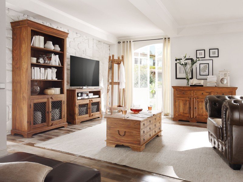 Helles Wohnzimmer mit grauem Sofa, Holz-Couchtisch, Teppich und Pflanzen – frühlingshafte Wohninspiration.