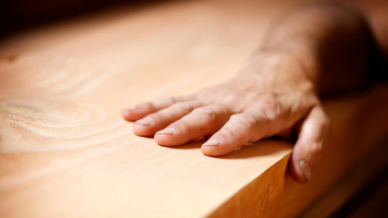 Hand berührt helle Holzoberfläche.