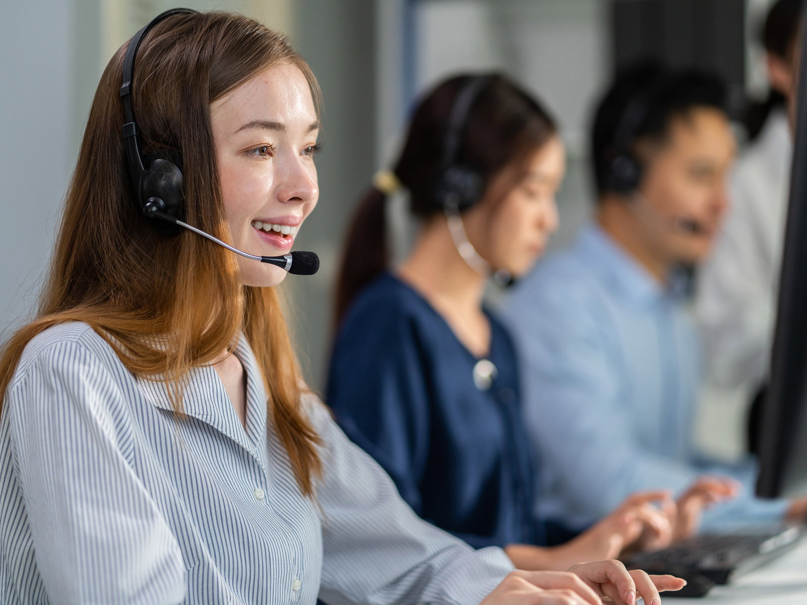 Mitarbeiterinnen und Mitarbeiter mit Headsets bei der telefonischen Kundenberatung