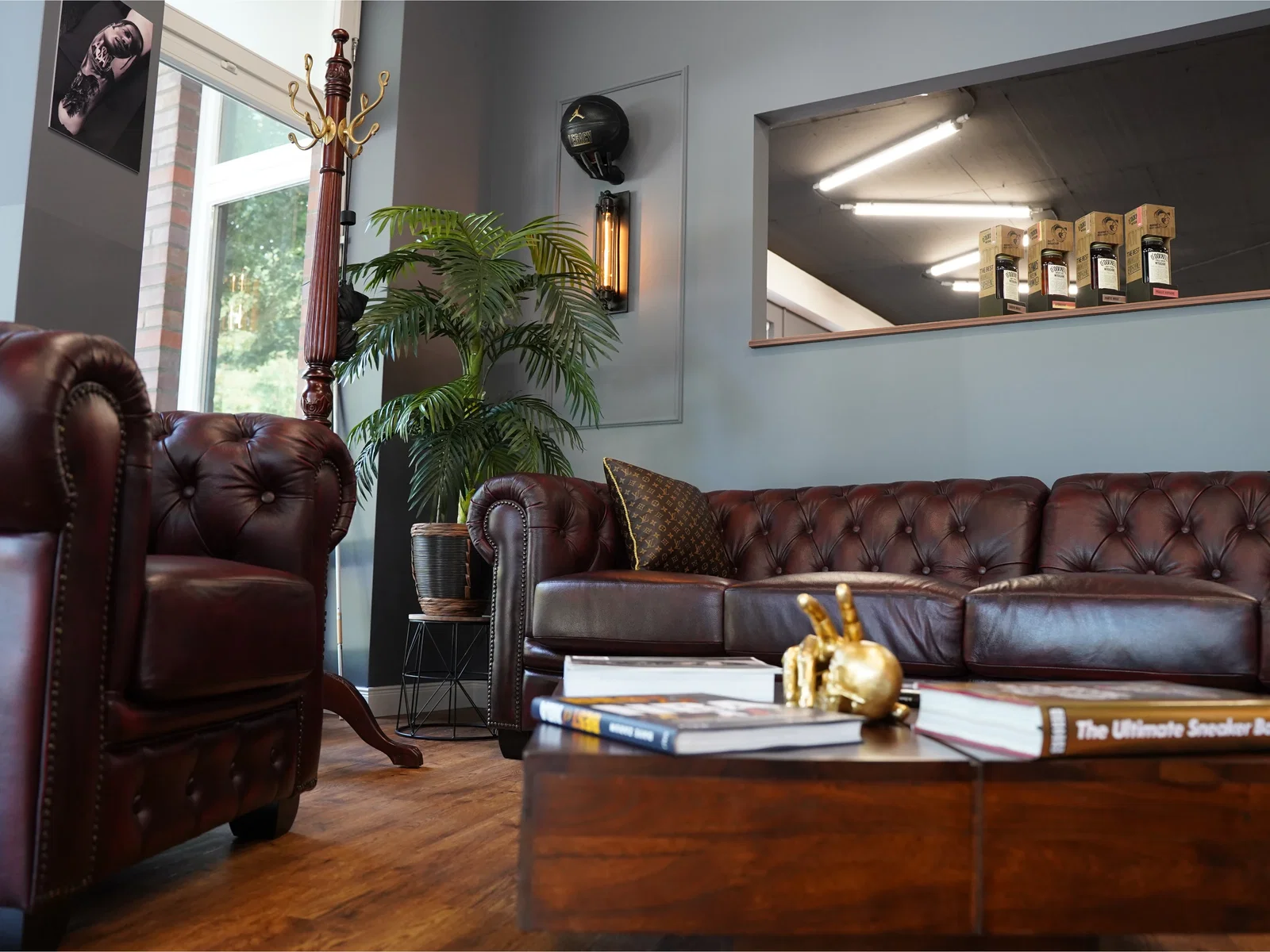 Chesterfield-Sofa und passender Ledersessel in Dunkelrot gestalten den gemütlichen Lounge- und Wartebereich im Tattoostudio Tattoo Highlights in Hamburg.