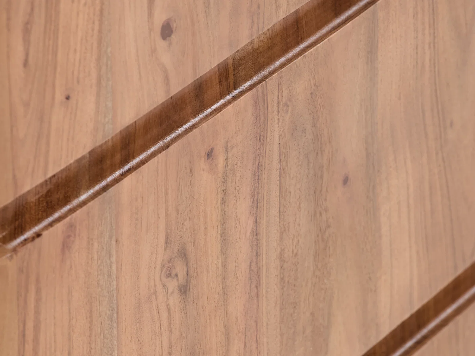 Detailaufnahme der lackierten Akazienholz-Oberfläche des Sideboards Kala in Braun, diagonale Frontansicht des Möbelstücks.