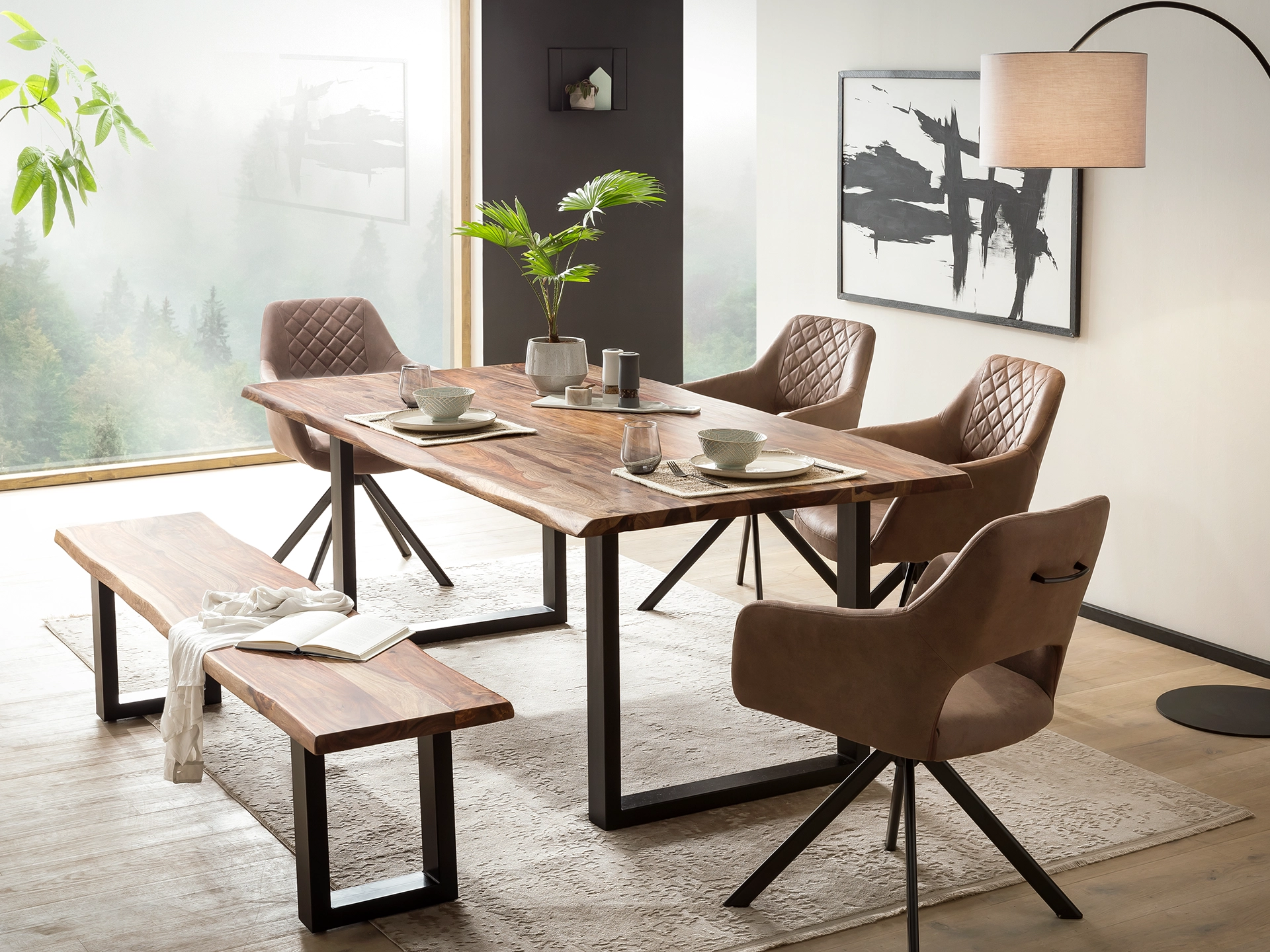 Ambienteaufnahme des Massivholztischs 'Bullwer' mit rustikaler Holzmaserung, warmen Brauntönen und schwarzem Industriegestell, gemütliche Esszimmer-Atmosphäre