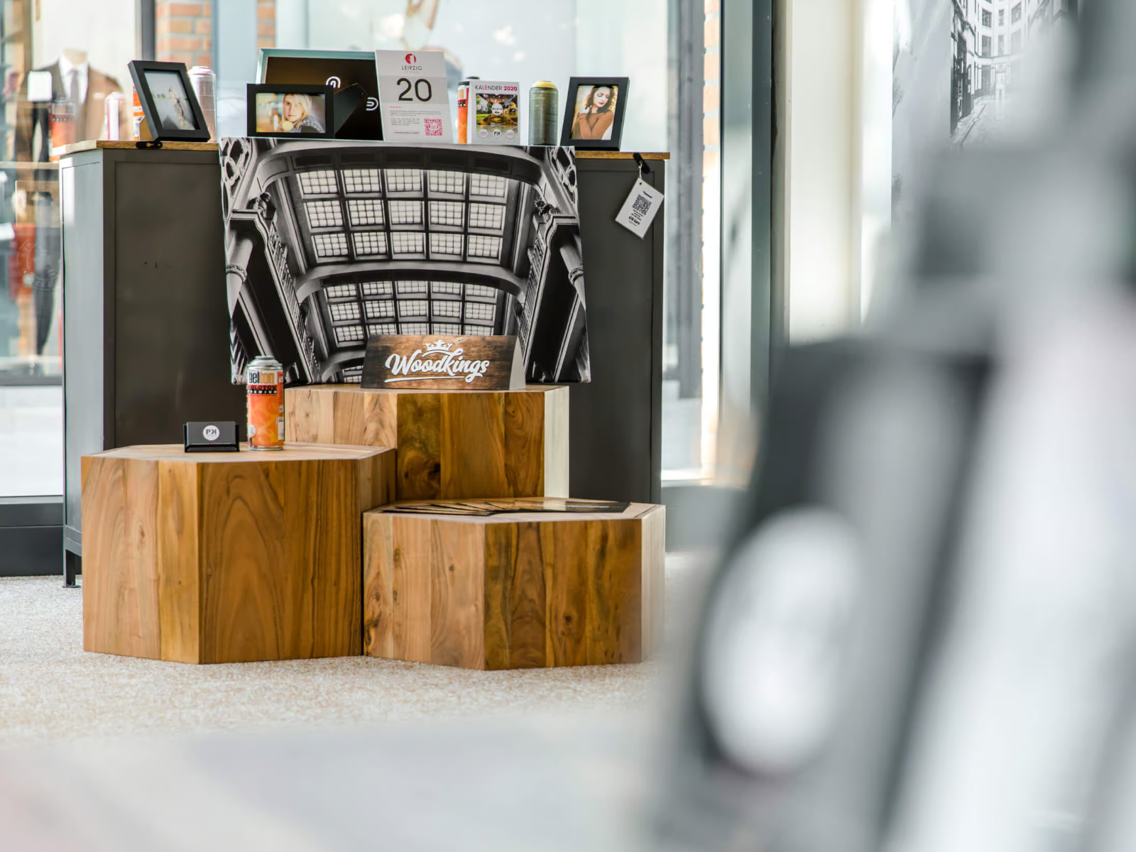 Drei massive Holzblöcke in unterschiedlichen Höhen vor einer großformatigen Schwarz-Weiß-Fotografie in der Galerie