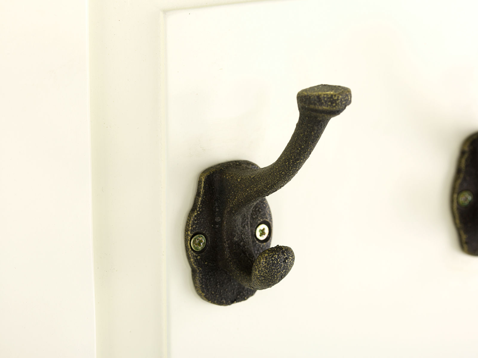 Detailbild: Schwarzer Metall-Kleiderhaken in 45°-Ansicht an weißem Garderobenpaneel Catana, Pinie/MDF, lackiert, B38 H135 T6 cm.