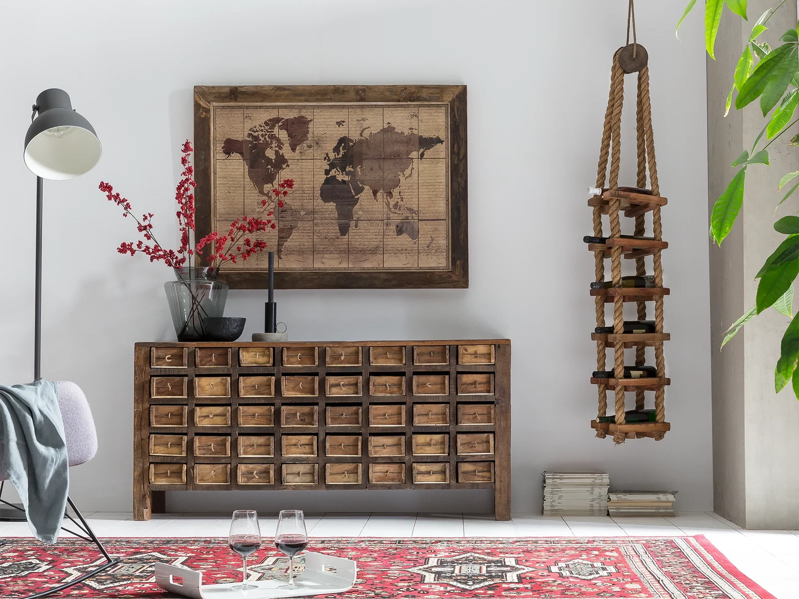 Sideboard Madurai aus Altholz mit zahlreichen kleinen Ziegelform-Schubladen, kombiniert mit Weltkarten-Wandbild und hängendem Weinregal