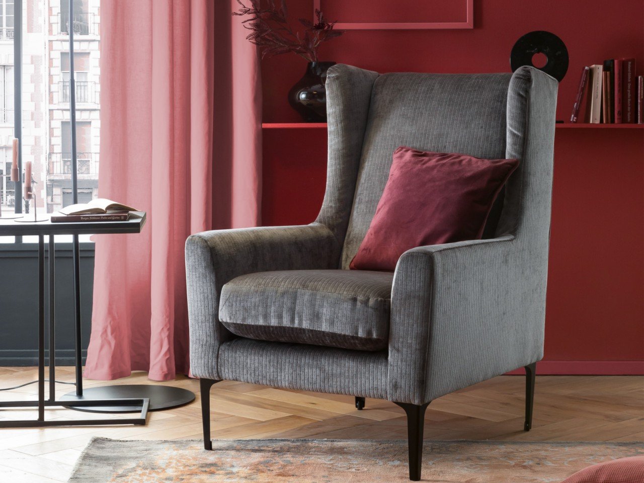 Graues Stoffsofa (Ecksofa) in hellem Wohnzimmer mit Kissen, Beistelltisch und Pflanze — modernes, gemütliches Interieur