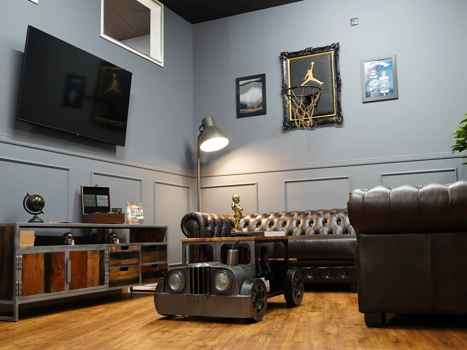 Lounge mit dunklem Chesterfield-Sofa, Holzmöbeln und Couchtisch in Fahrzeugoptik