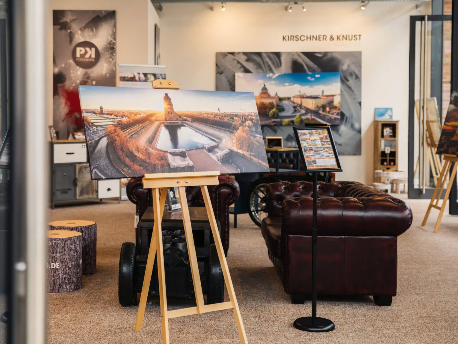 Einblick in den Showroom Kirschner & Kunst in Brehna mit großformatigem Gemälde auf einer Staffelei, dunkelbraunem Chesterfield-Ledersofa und weiteren Kunstwerken im Ausstellungsraum.