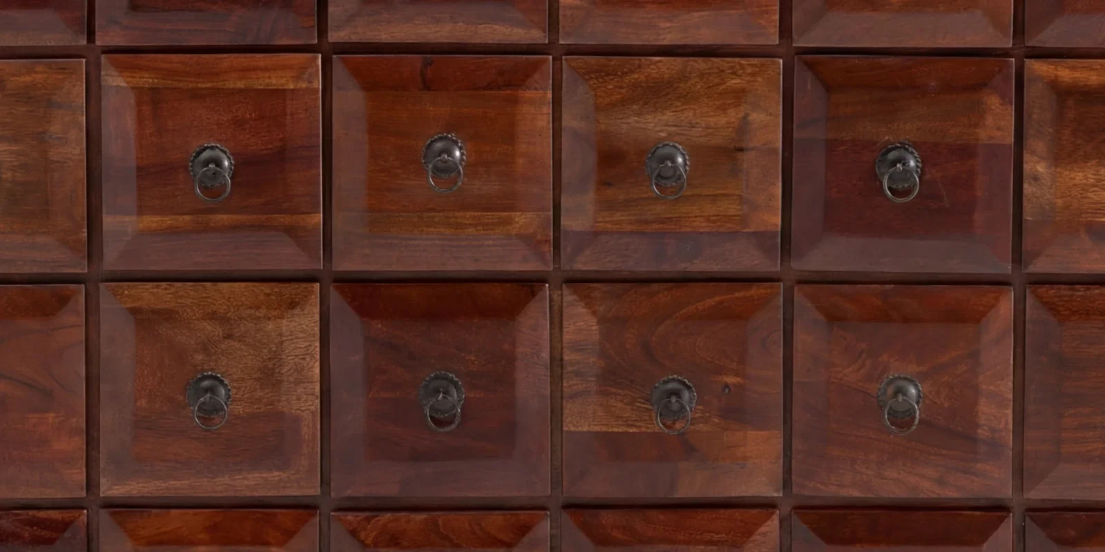 Detailaufnahme einer Kommode aus dunklem Massivholz mit quadratischen Schubladenfronten und Ringgriffen aus Metall.