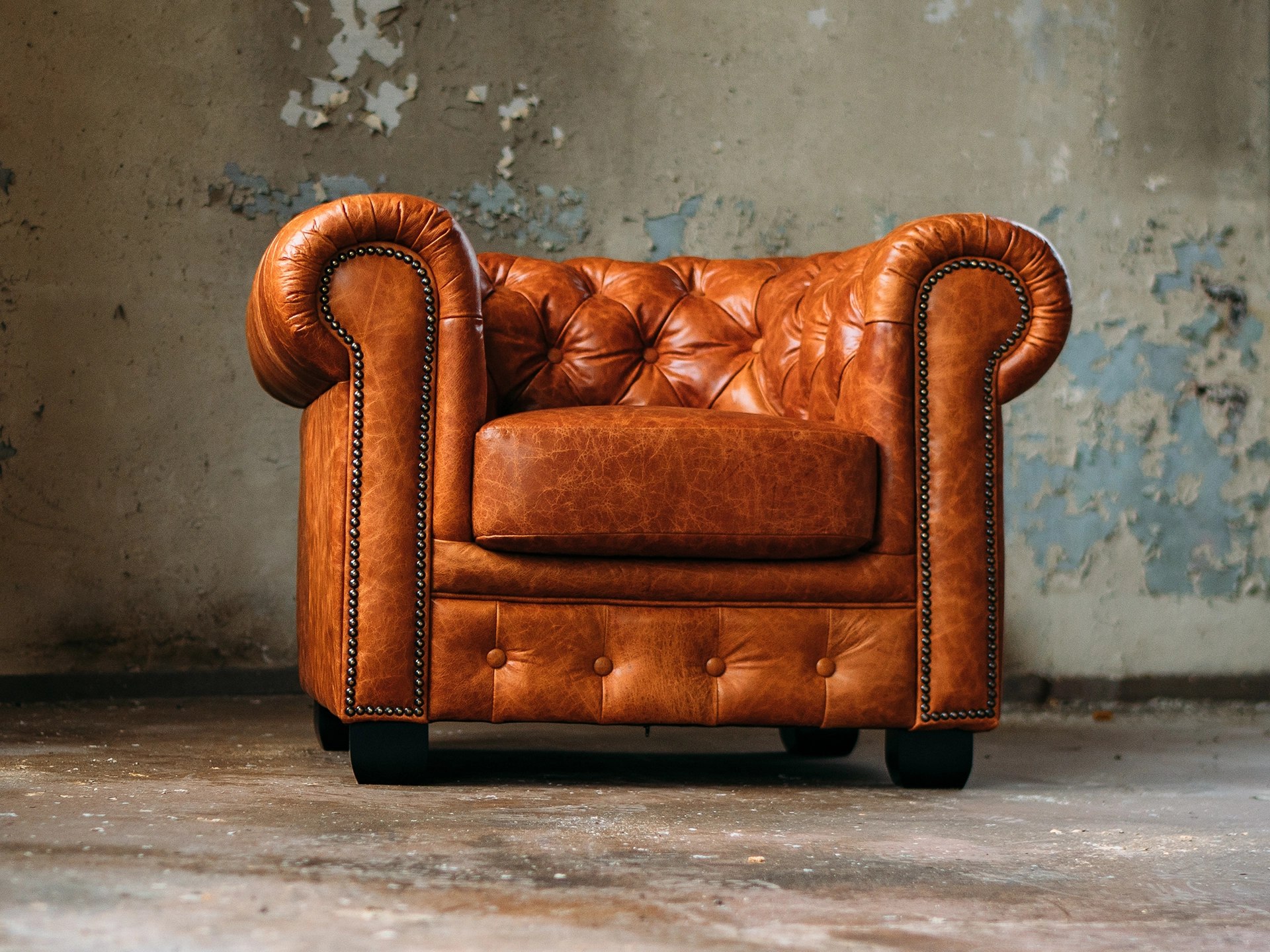 Klassisches Chesterfield-Ledersofa in gemütlichem Vintage-Ambiente, tief gesteppt mit Holzfüßen – elegantes Wohnzimmer-Sitzmöbel
