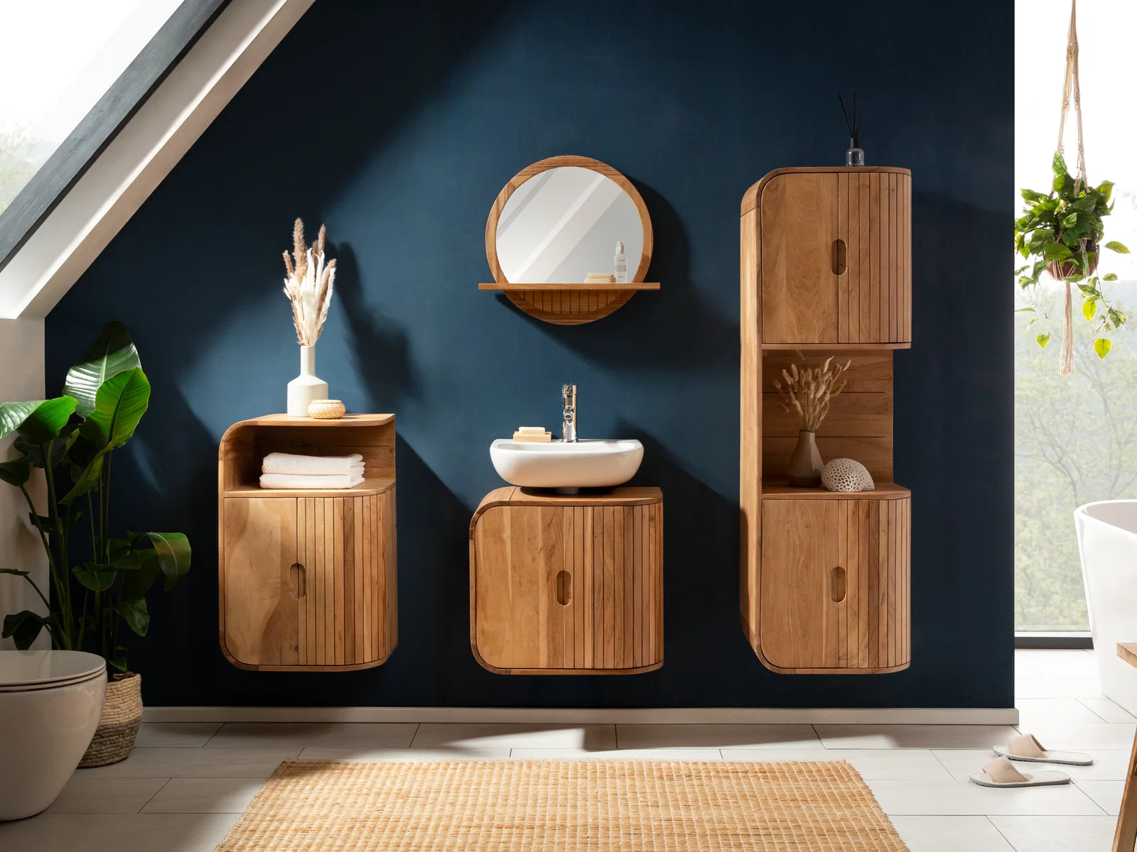 Modernes Badezimmer mit hängenden Badmöbeln aus Holz, Waschbeckenunterschrank, Hochschrank und rundem Spiegel vor dunkelblauer Wand