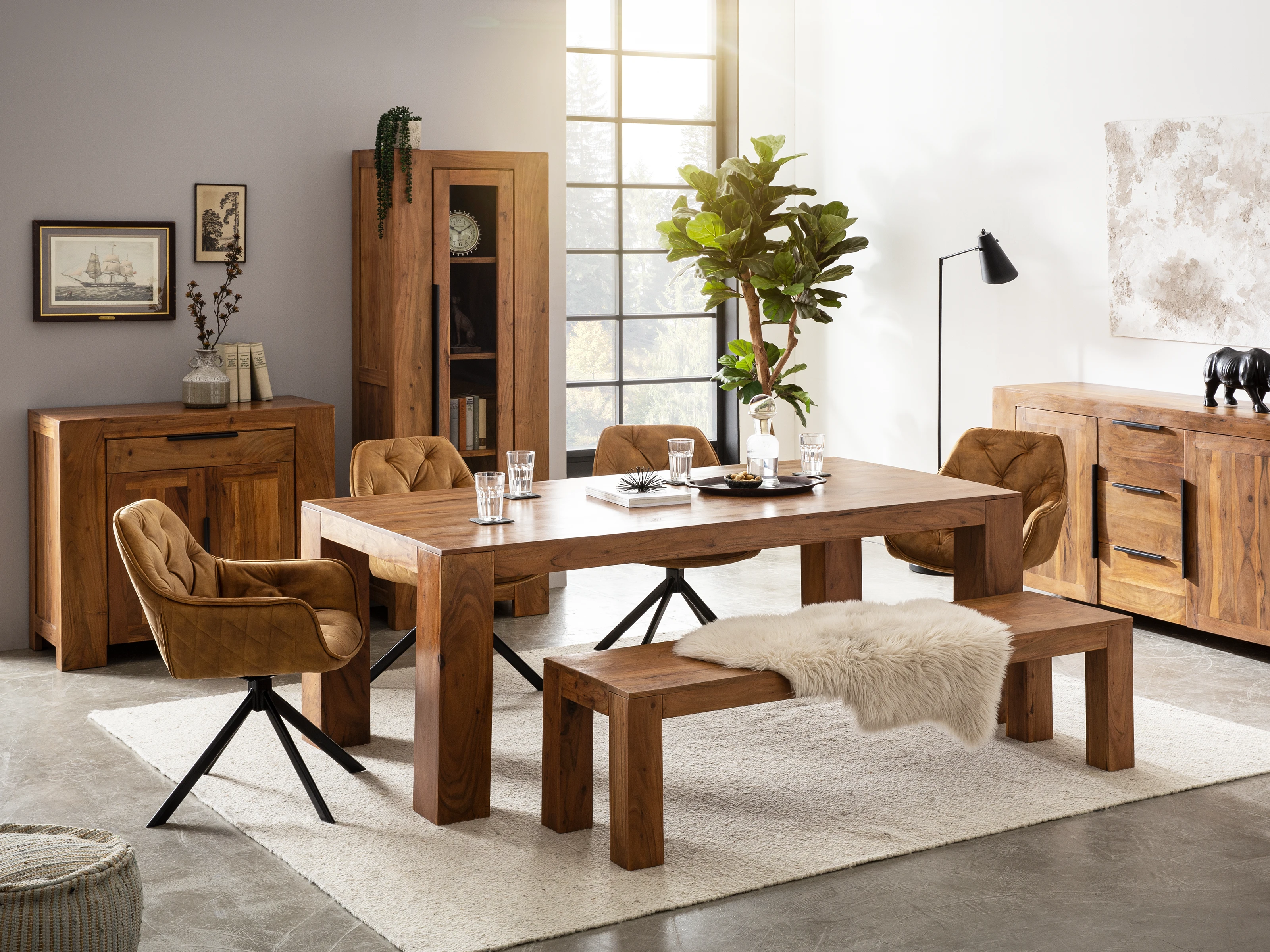 Essbereich mit modernem Holztisch, gepolsterten Stühlen und Bank auf hellem Teppich. Links steht die Kommode Osbon mit zwei Türen und einer Schublade aus braun lackierter Akazie. Oberflächen dekoriert mit Pflanzen und Bildern. Essbereich mit modernem Holztisch, gepolsterten Stühlen und Bank auf hellem Teppich. Links steht die Kommode Osbon mit zwei Türen und einer Schublade aus braun lackierter Akazie. Oberflächen dekoriert mit Pflanzen und Bildern.