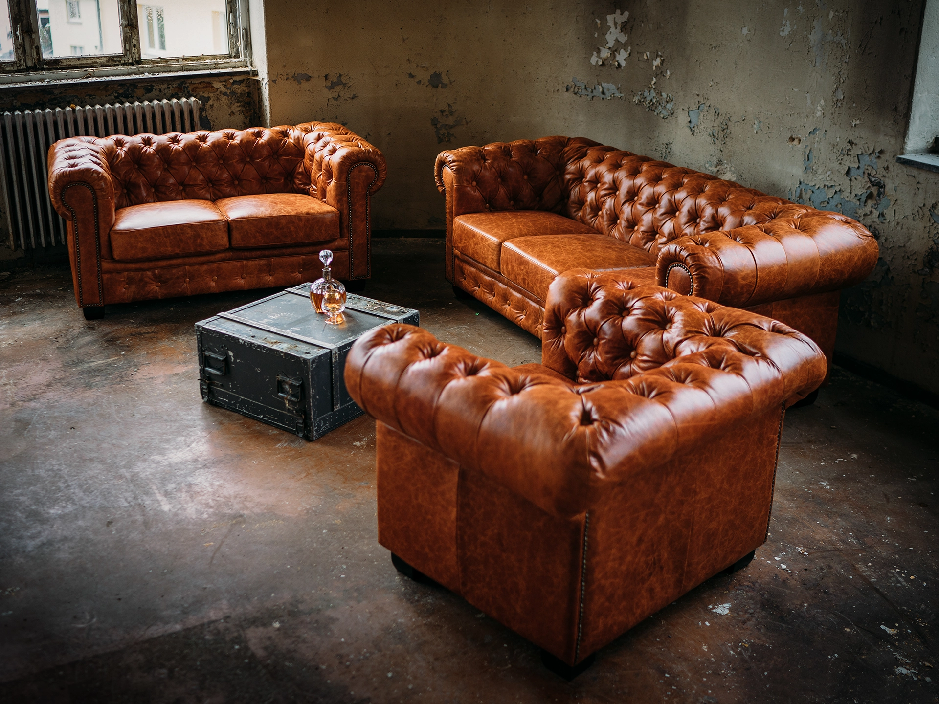 Braunes Chesterfield-Ledersofa im Wohnambiente mit klassischer Knopfheftung, gewölbter Rückenlehne und sichtbaren Holzfüßen — warmes, elegantes Interieur.
