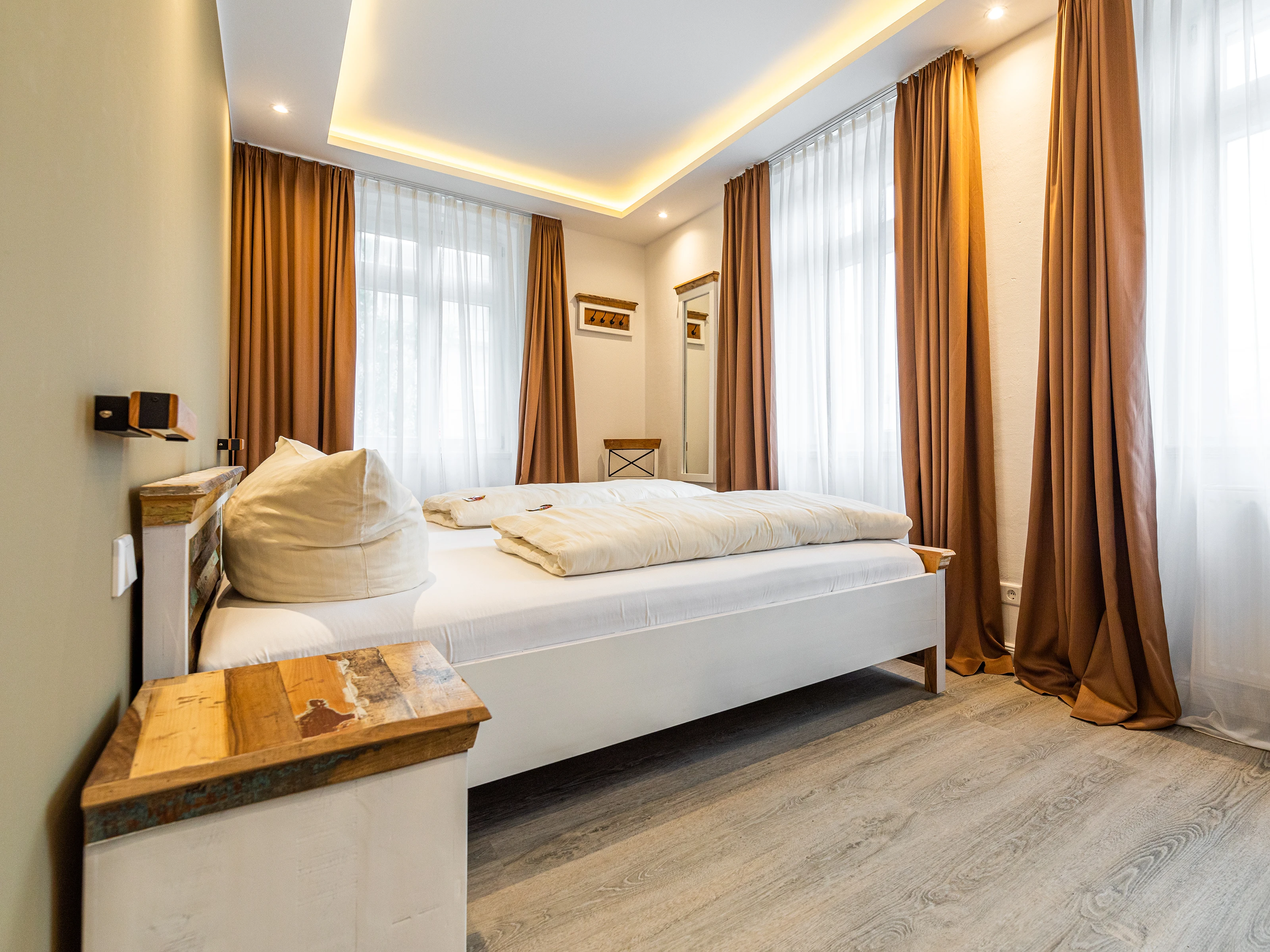 Hotelzimmer mit Holzbett und Nachttischen, warmes, modernes Ambiente, natürliche Holztöne, dezente Beleuchtung und elegante Textilien