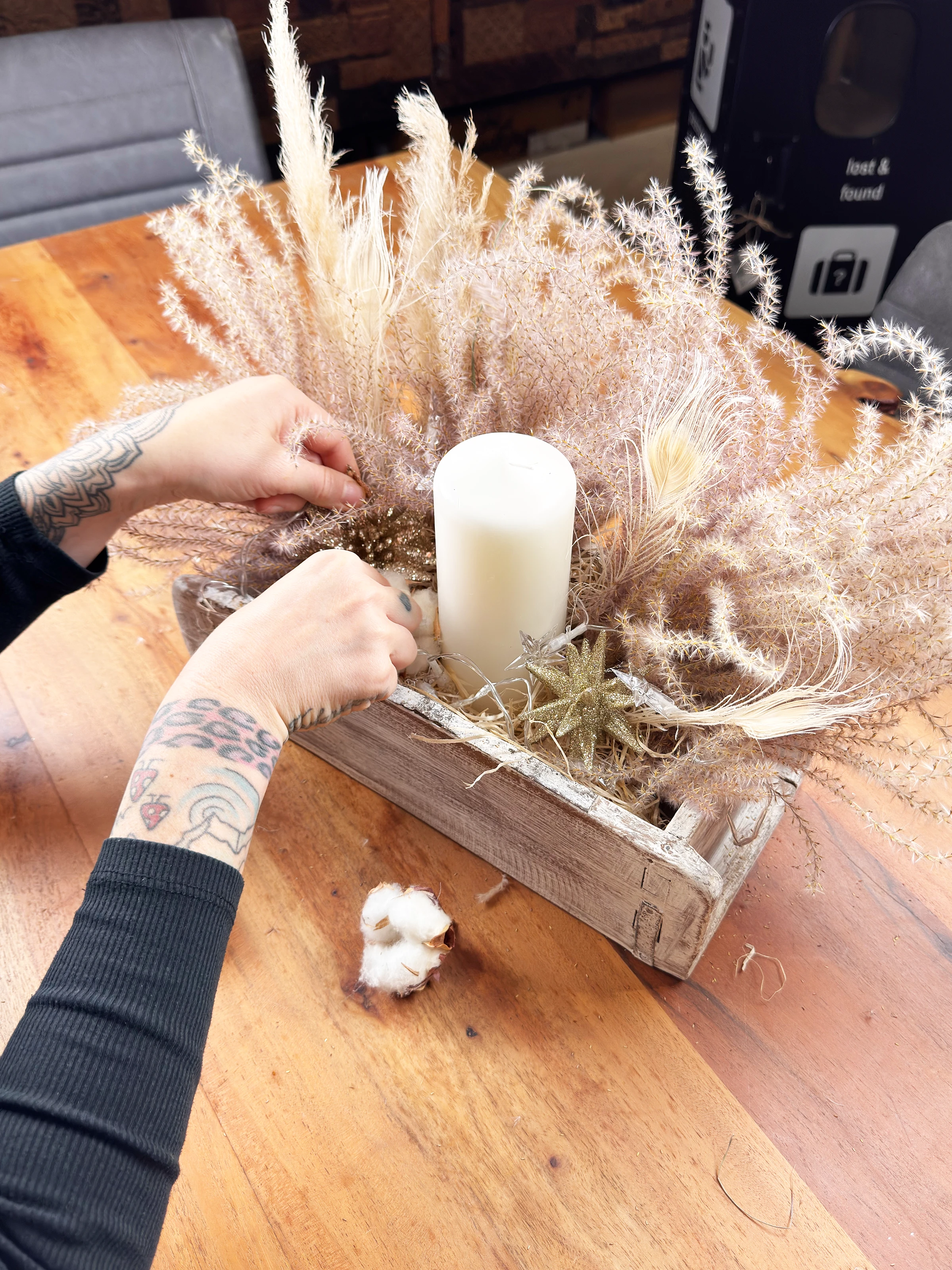 Boho-Rattansessel mit hellen Kissen in natürlichem, luftigen Wohnzimmer-Ambiente mit Pflanzen und Holzdetails