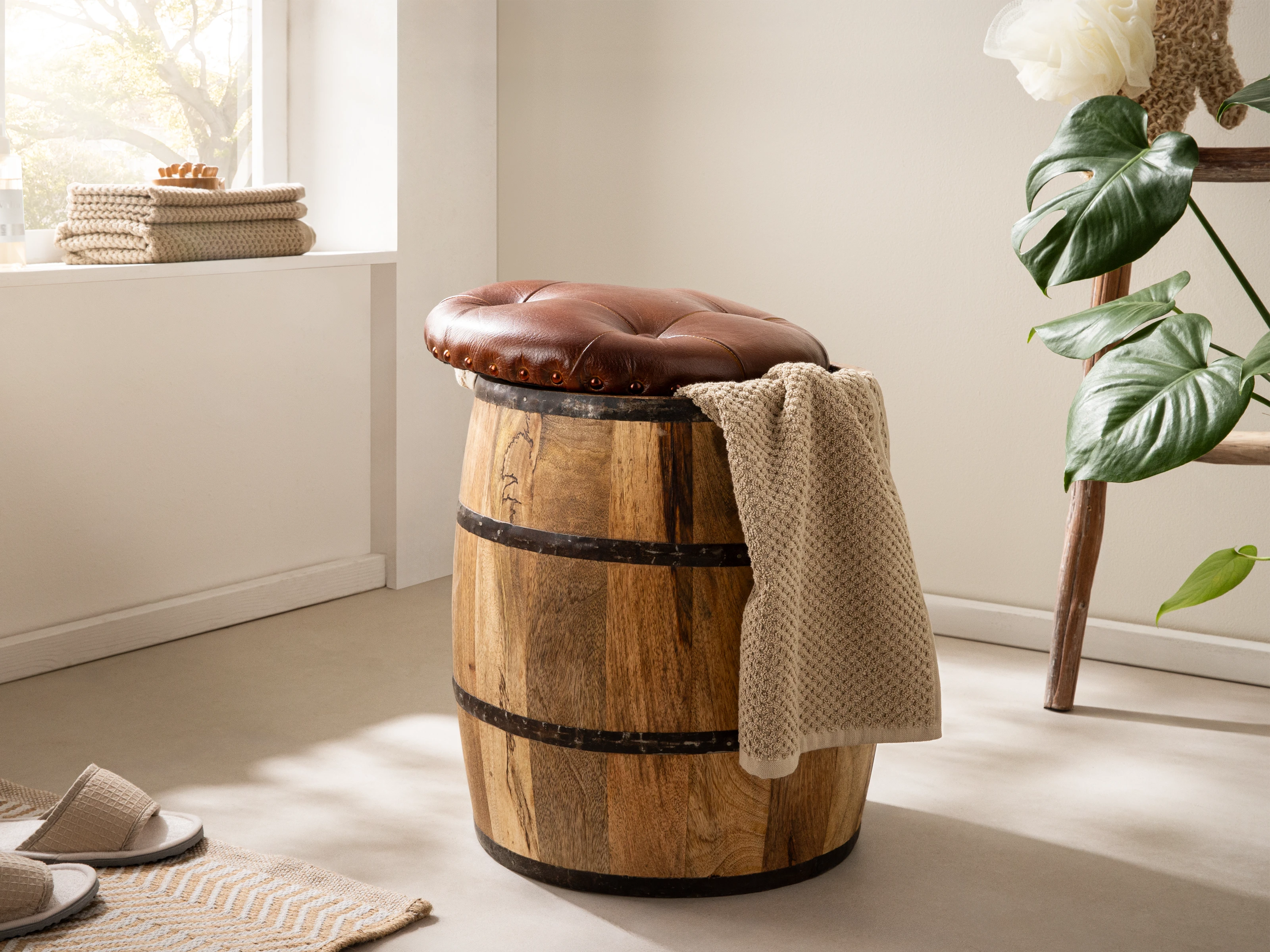 Holzfass Flip Sitzhocker in 45°-Ansicht: Mangoholzfass mit braunem Lederpolster und Strickdecke als Wohnbeispiel-Sitzmöbel