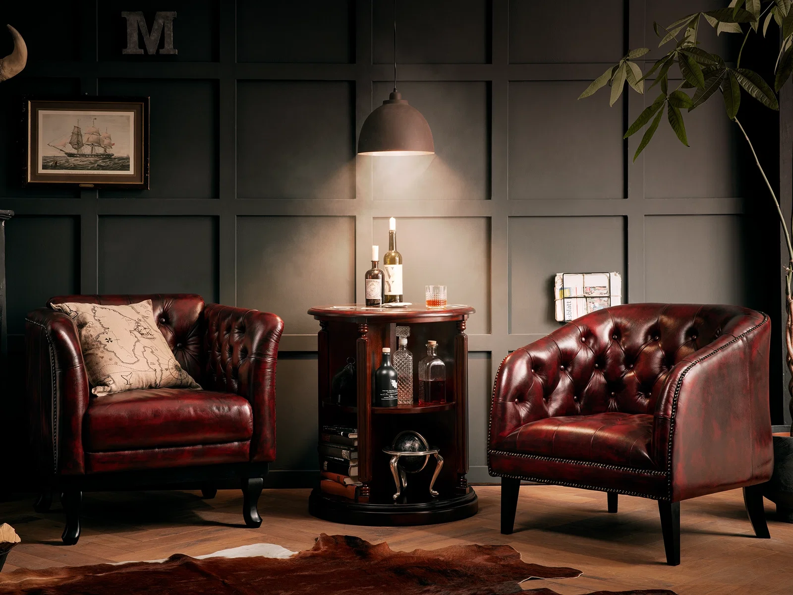 Zwei Chesterfield Sessel Oakland aus rotem Echtleder mit Knopfheftung in einem dunkel eingerichteten Wohnzimmer