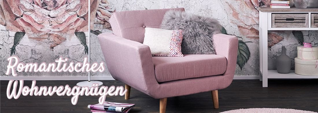 Romantisches Landhaus-Wohnzimmer mit weißer Vintage-Couch, Holzboden, floralen Kissen und zarten Dekoblumen, helle Country-Atmosphäre.